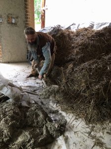 Lasse Holmes shovels clay during the straw and clay insulation workshop at Northern Susitna Institute. Photo: Katie Writer - KTNA