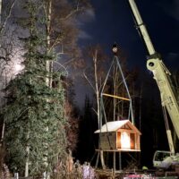 Pit toilets being hoisted by a crane and lowered into place at the Whigmi Trailhead parking area.